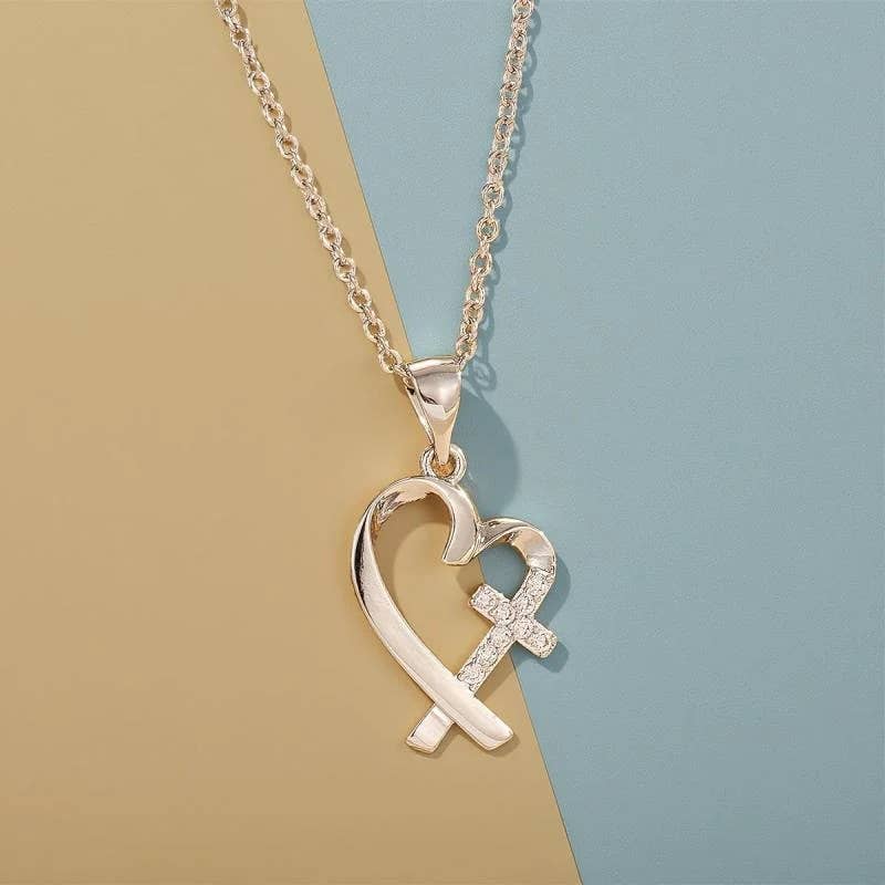 Gold necklace with a heart and cross pendant on a two-tone background