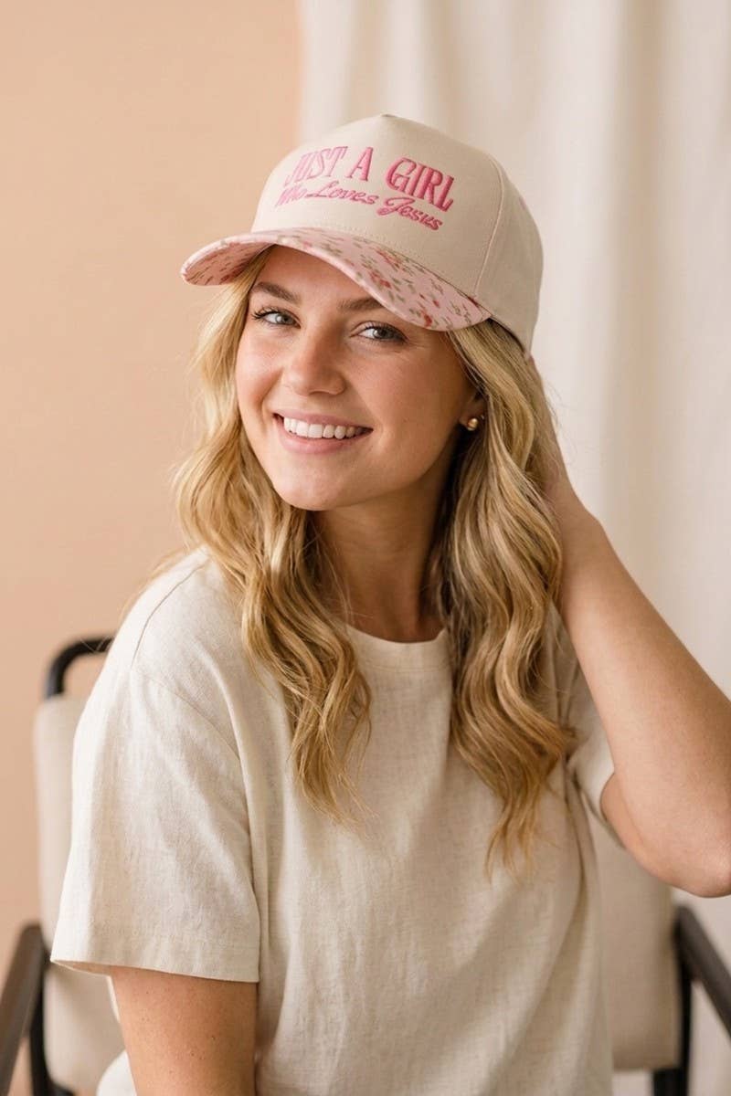 Woman wearing a pink cap with text, smiling against a neutral background