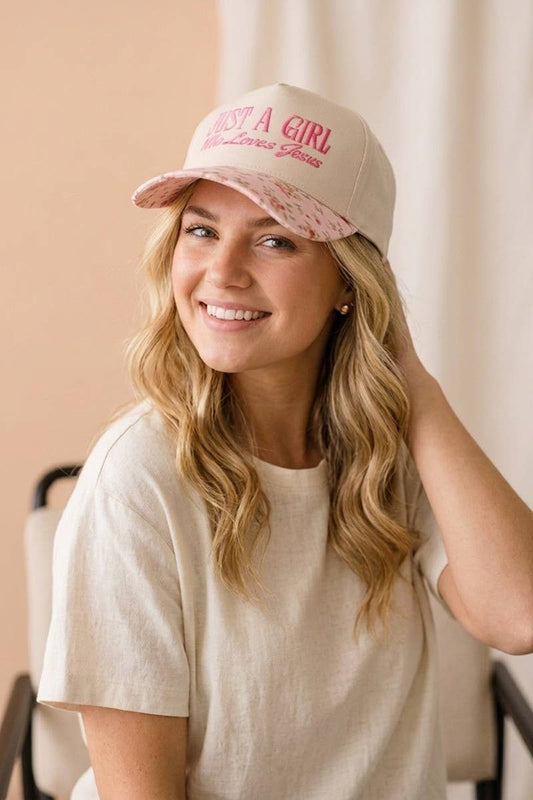 Woman wearing a pink cap with text, smiling against a neutral background
